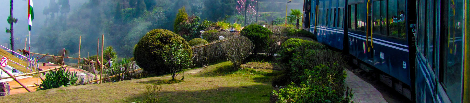 Train Passing A Beautiful Garden And Entering Into Fog. Surrounded By Tree Covered Mountains Shutterstock 184285343