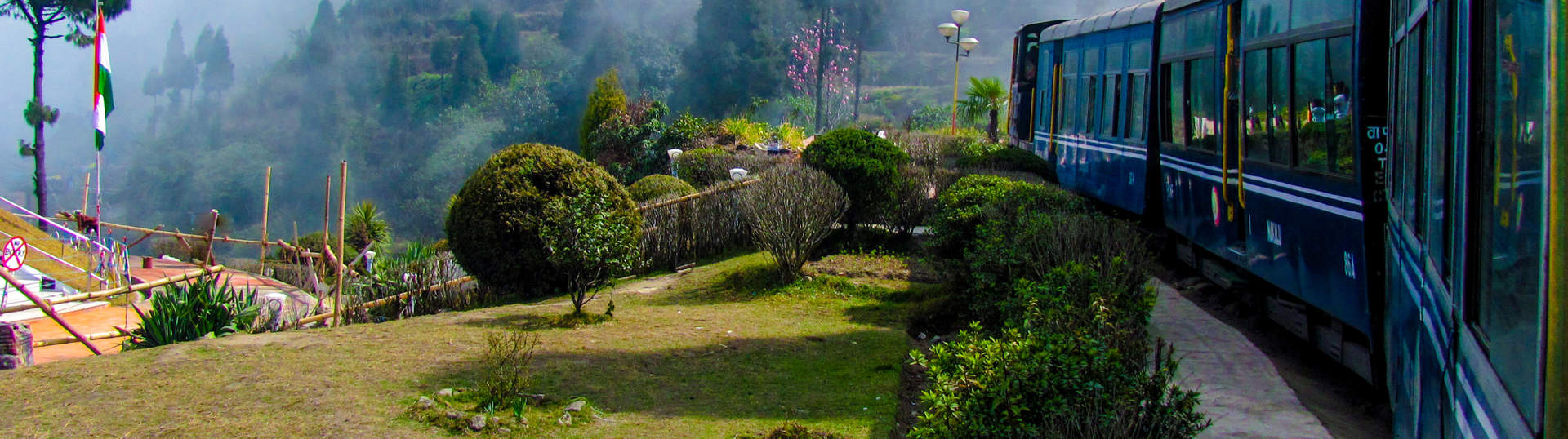 Train Passing A Beautiful Garden And Entering Into Fog. Surrounded By Tree Covered Mountains Shutterstock 184285343