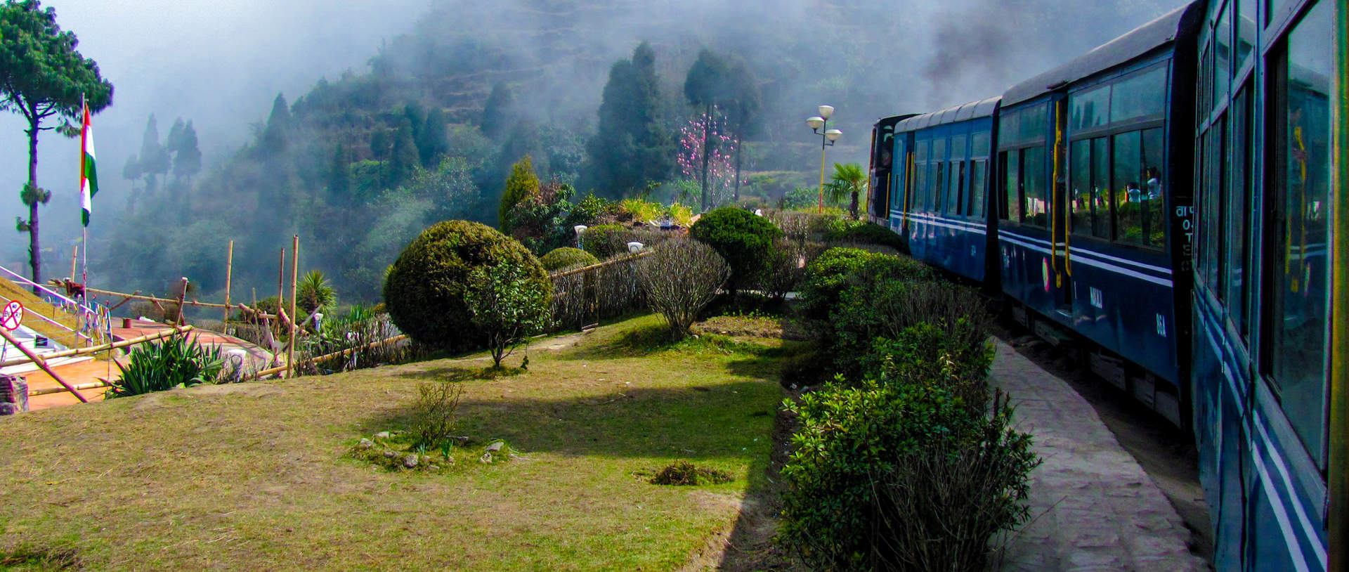Train Passing A Beautiful Garden And Entering Into Fog. Surrounded By Tree Covered Mountains Shutterstock 184285343
