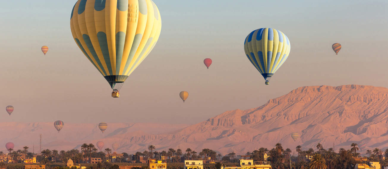 Hot Air Balloons Over Nile River And Valley Of Kings In Luxor At Sunrise In Egypt